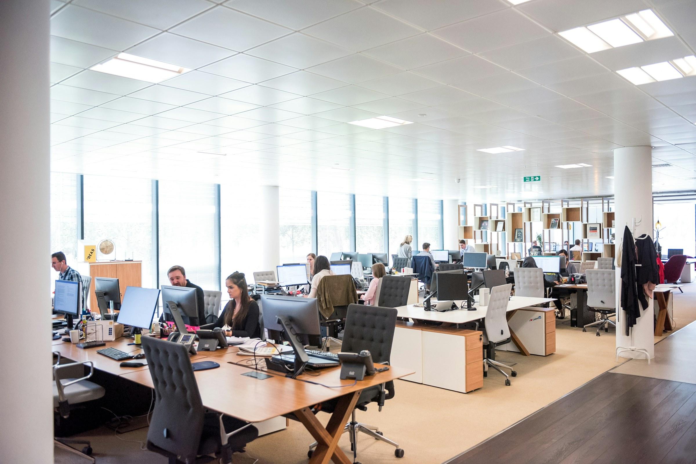A bright open-plan office floor with teams working at their desks